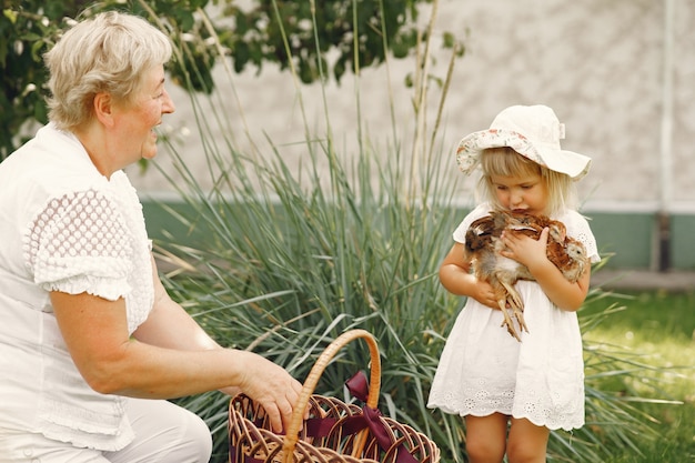 Famiglia in un anno indietro. Nipote con la nonna. Persone con un piccolo pollo.