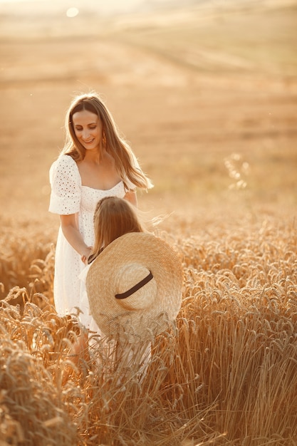 Famiglia in un campo di grano. Donna in abito bianco. Ragazza con cappello di paglia.