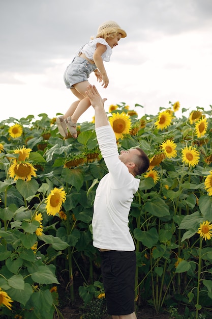 Famiglia in un campo estivo con girasoli. Padre in camicia bianca. Bel bimbo.