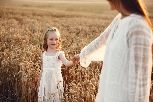 Famiglia in un campo estivo. Foto sensuale. Piccola ragazza carina. Donna in abito bianco.