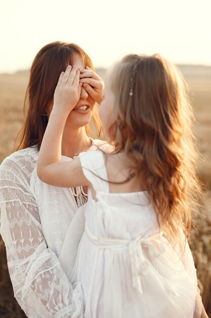 Famiglia in un campo estivo. Foto sensuale. Piccola ragazza carina. Donna in abito bianco.