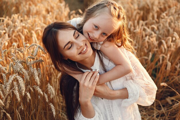 Famiglia in un campo estivo. Foto sensuale. Piccola ragazza carina. Donna in abito bianco.