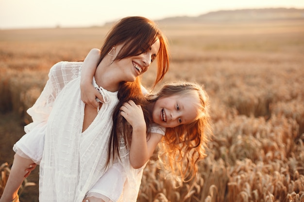 Famiglia in un campo estivo. Foto sensuale. Piccola ragazza carina. Donna in abito bianco.