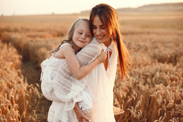 Famiglia in un campo estivo. Foto sensuale. Piccola ragazza carina. Donna in abito bianco.