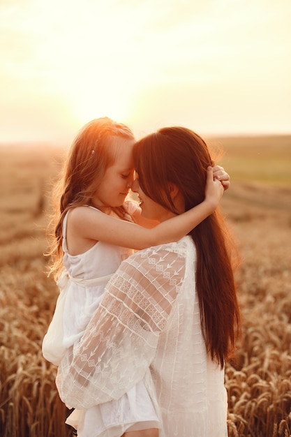 Famiglia in un campo estivo. Foto sensuale. Piccola ragazza carina. Donna in abito bianco.