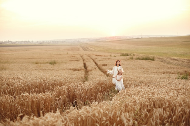 Famiglia in un campo estivo. Foto sensuale. Piccola ragazza carina. Donna in abito bianco.