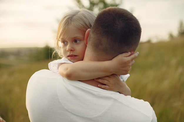 Famiglia in un campo estivo. Padre in camicia bianca. Figlia carina.