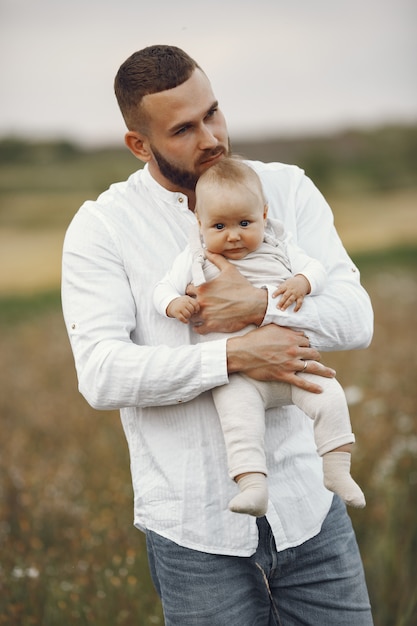 Famiglia in un campo estivo. Padre in camicia bianca. Figlia neonata carina.