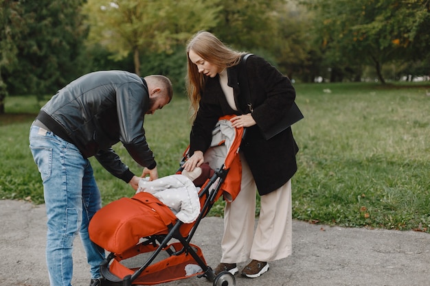 Famiglia in un parco d'autunno. Uomo in giacca nera. Bambina sveglia con i genitori.
