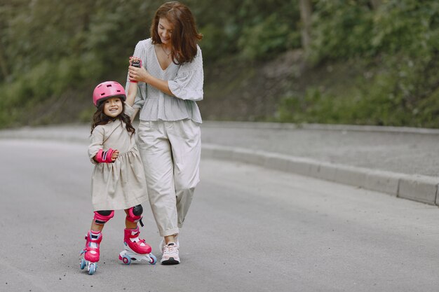 Famiglia in un parco estivo. Madre in camicetta. Bambina con un rullo.