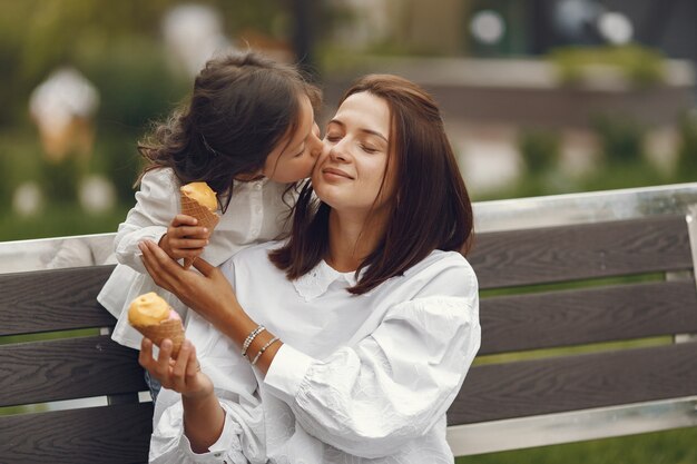 Famiglia in una città. La bambina mangia il gelato. Madre con figlia seduta su una panchina.