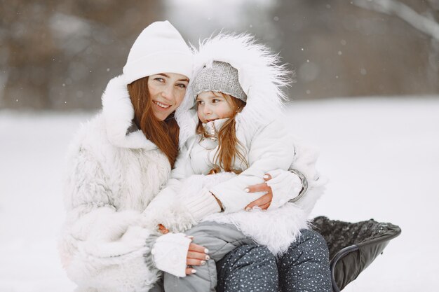 Famiglia in vacanza di Natale in famiglia. Donna e bambina in un parco. Persone con la slitta.