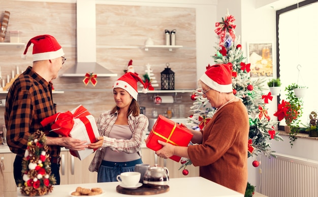 Famiglia multigenerazionale che celebra il natale con scatole regalo