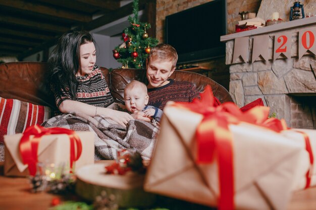 Famiglia seduta su un divano visto attraverso doni marrone con nastri rossi