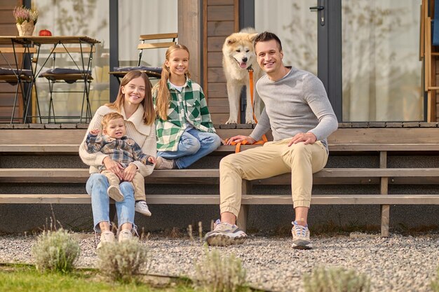 Famiglia seduta sui gradini che guarda l'obbiettivo e il cane