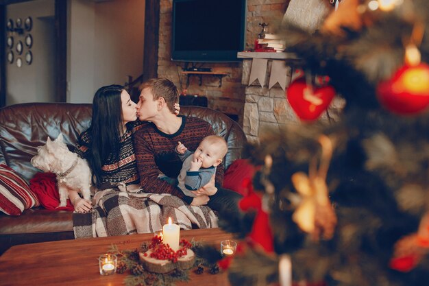 Famiglia seduta sul divano con albero di Natale fuori fuoco in fronte