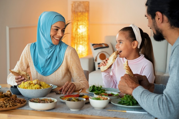 Famiglia sorridente che mangia insieme colpo medio