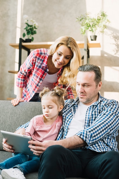 Famiglia sorridente che per mezzo insieme della compressa digitale a casa