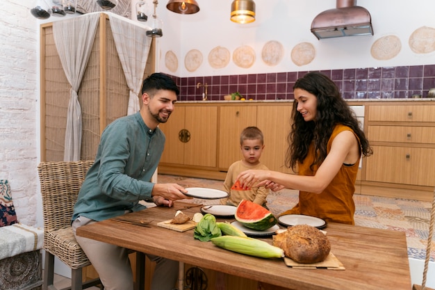 Famiglia sorridente di vista laterale che si siede al tavolo