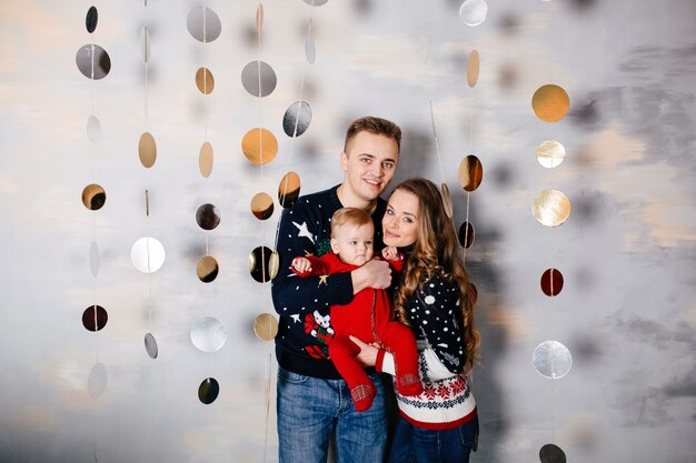 Famiglia sorridente felice allo studio su priorità bassa dell&#39;albero di Natale con il regalo