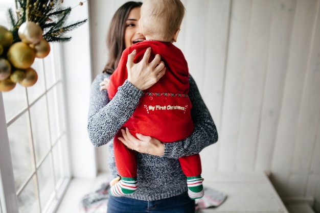 Famiglia sorridente felice allo studio su priorità bassa dell&#39;albero di Natale con il regalo