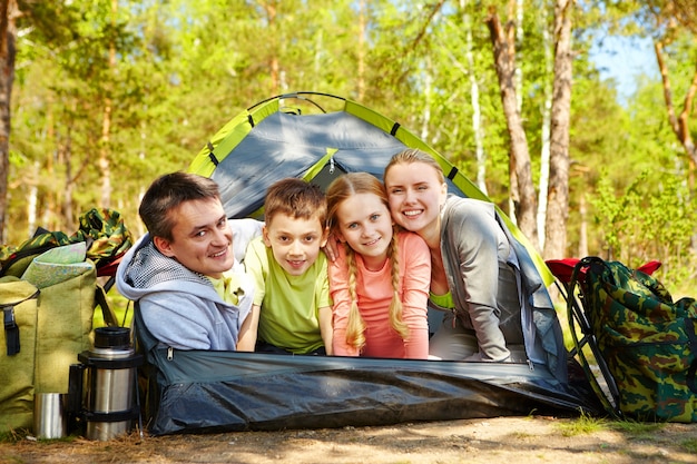 Famiglia sorridente nella tenda sul prato soleggiato