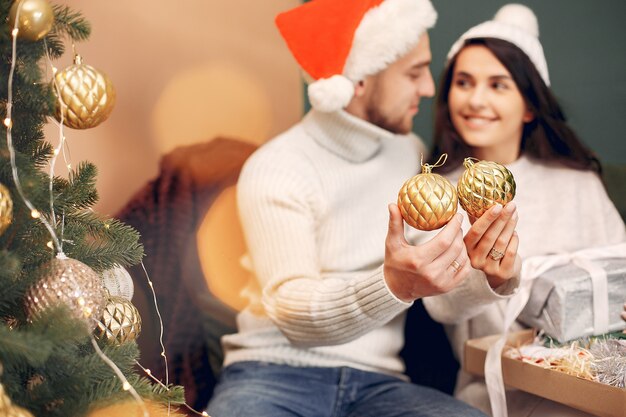 Famiglia sveglia che si siede a casa vicino all'albero di Natale