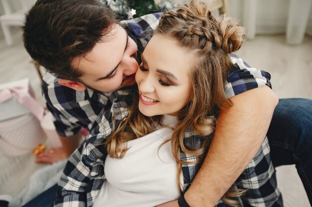 Famiglia sveglia che si siede vicino all&#39;albero di Natale