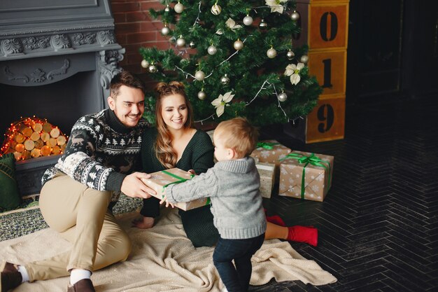 Famiglia sveglia che si siede vicino all&#39;albero di Natale