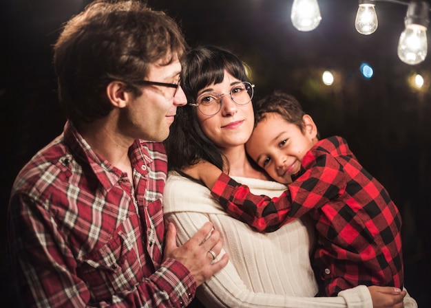 Famiglia sveglia sotto il servizio fotografico di natale delle lampadine