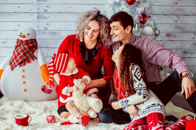 Famiglia vestita fantasia pone prima albero di Natale bianco