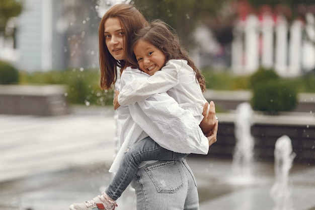 Famiglia vicino alla fontana della città. Madre con la figlia che gioca con l'acqua.