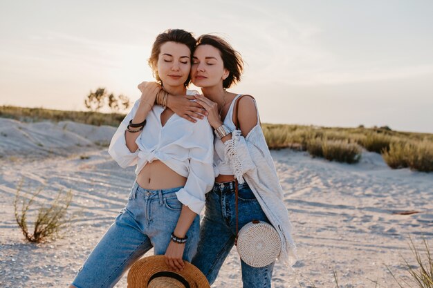 Fantastiche due giovani donne che si divertono sulla spiaggia al tramonto, amore lesbico gay