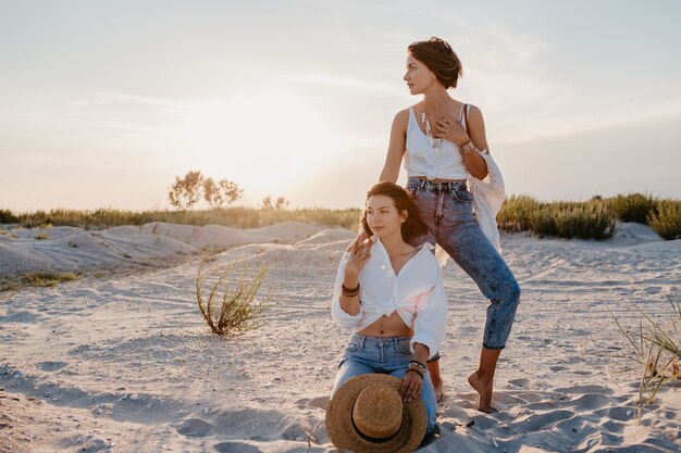 Fantastiche due giovani donne che si divertono sulla spiaggia al tramonto, amore lesbico gay