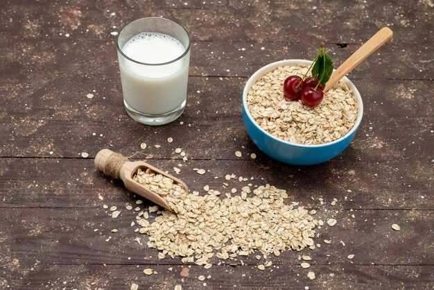 Farina d'avena cruda di vista superiore dentro il piatto bianco con latte su marrone, prima colazione cruda di salute dell'alimento