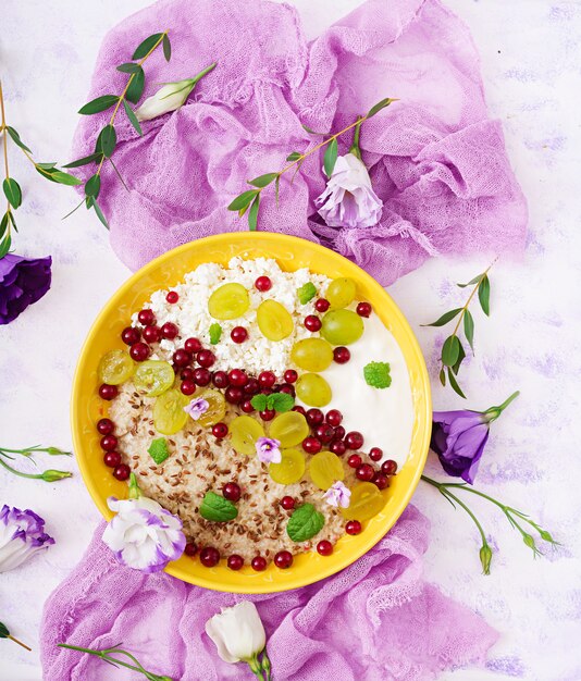 Farina d'avena deliziosa e sana con uva, yogurt e ricotta. Colazione salutare. Cibo fitness. Nutrizione appropriata. Disteso. Vista dall'alto.