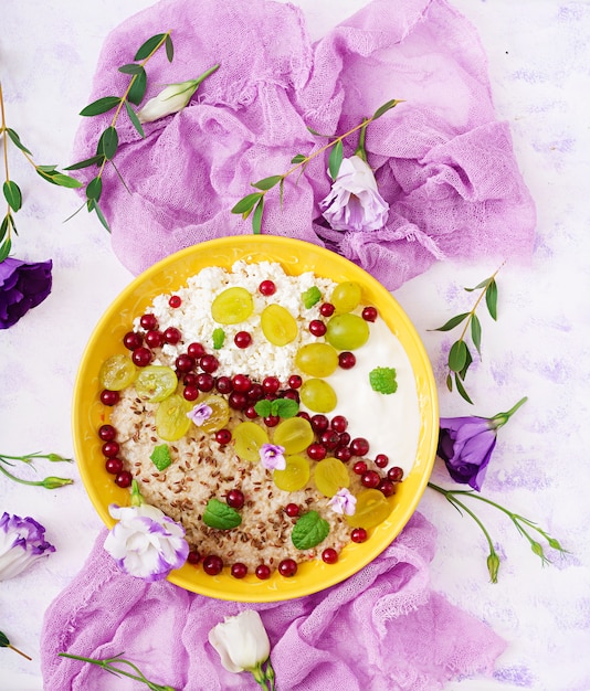 Farina d'avena deliziosa e sana con uva, yogurt e ricotta. Colazione salutare. Cibo fitness. Nutrizione appropriata. Disteso. Vista dall'alto.