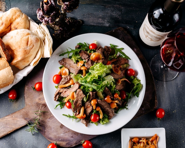 Farina di carne vista dall'alto con verdure all'interno del piatto bianco sulla scrivania marrone e superficie scura