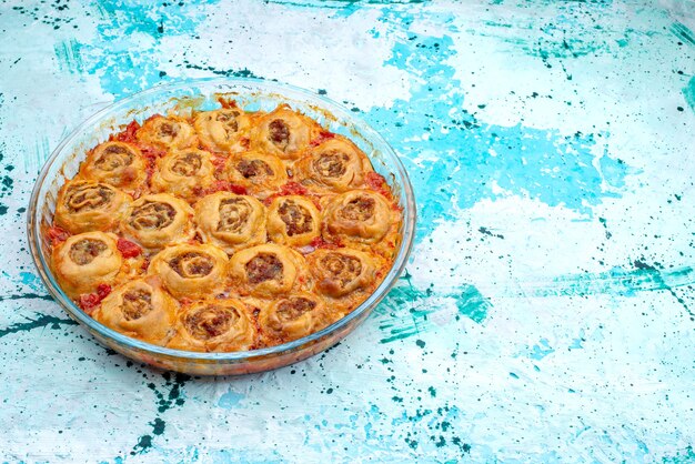 farina di pasta cotta con carne macinata e salsa di pomodoro all'interno di una teglia di vetro su un impasto di carne blu brillante, cottura da forno