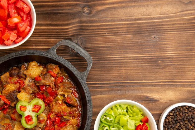 Farina di verdure cotte vista dall'alto con insalata di peperoni affettati sulla scrivania marrone