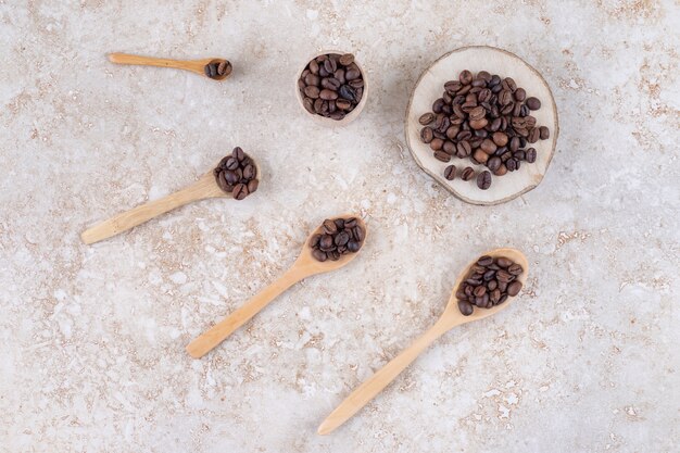 Fasci profumati di chicchi di caffè su cucchiai, un pezzo di legno e una tazzina