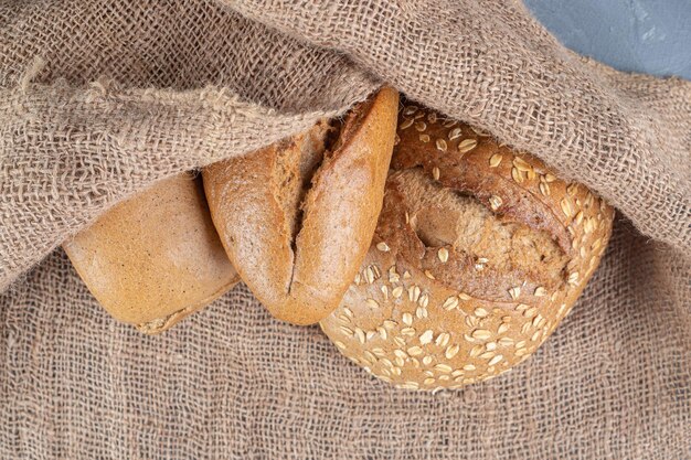 Fascio di pagnotte di pane ricoperte da un pezzo di tessuto sul tavolo di marmo.