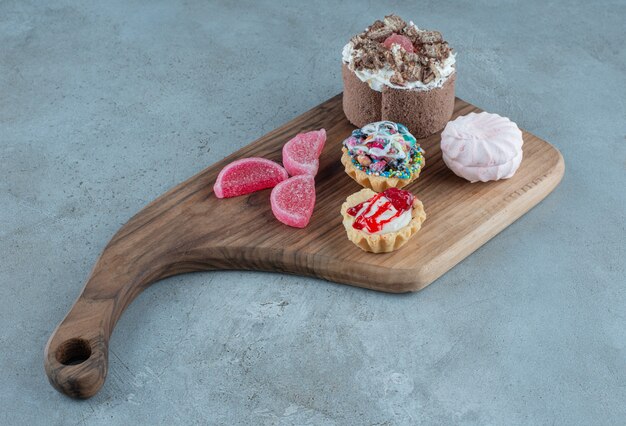 Fascio di vari dolci e marmellate su una tavola di legno su sfondo marmo. Foto di alta qualità