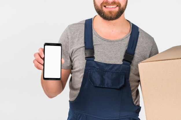 Fattorino che tiene grande scatola e smartphone con lo schermo in bianco