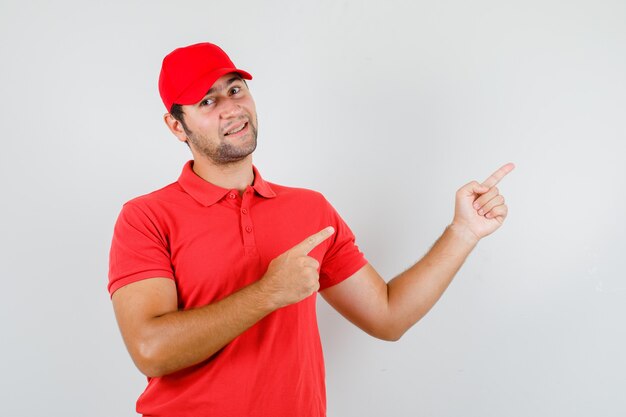 Fattorino in maglietta rossa, berretto che punta le dita e sembra allegro