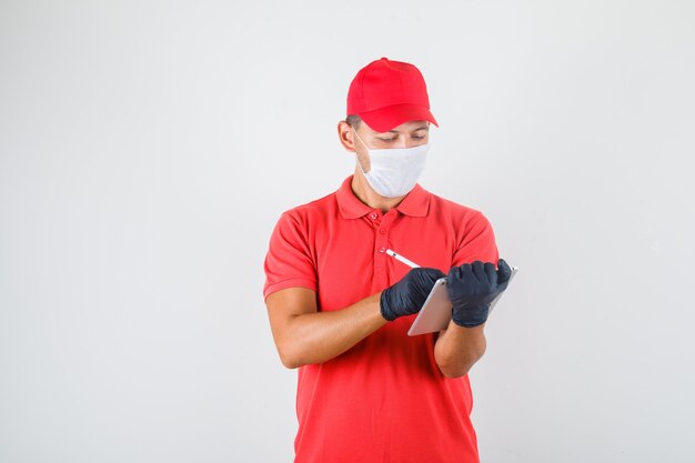 Fattorino prendere appunti su tablet con penna digitale in uniforme rossa