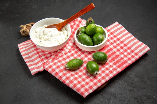 Feijoa verde fresco di vista frontale con crema sulla salute esotica della frutta di superficie scura