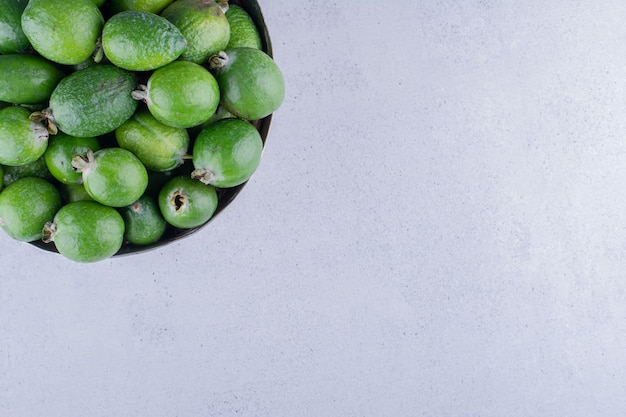 Feijoas accatastati in un vaso di metallo su sfondo marmo. Foto di alta qualità