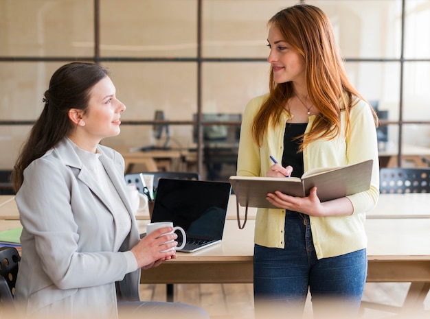 Felice attraente due donna che lavora insieme sul posto di lavoro