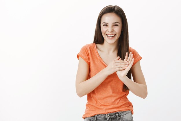 Felice bella ragazza caucasica ridendo e battendo le mani, applaudendo